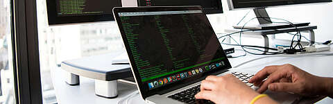 Eine Nahaufnahme eines Computerbildschirms, auf dem Codiersoftware mit leuchtend farbigem Text des Ruby-on-Rails-Codes angezeigt wird, hauptsächlich in Grün, Weiß und Orange auf dunklem Hintergrund.