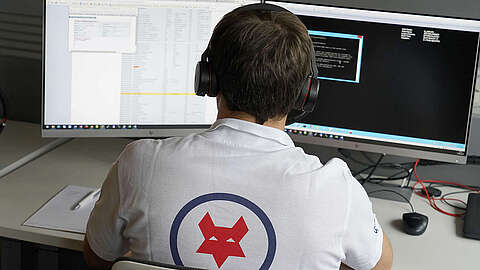 Ticketmanagement - Die Ausgangslage Q-FOX Mitarbeiter mit Headset sitzt an seinem Computer und bearbeitet IT-Service-Anfragen