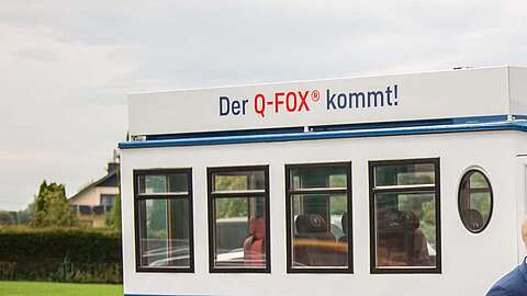 3 Leute stehen vor einem Q-FOX® Bus