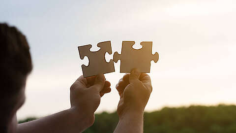 Zwei Puzzleteile werden zusammengehalten